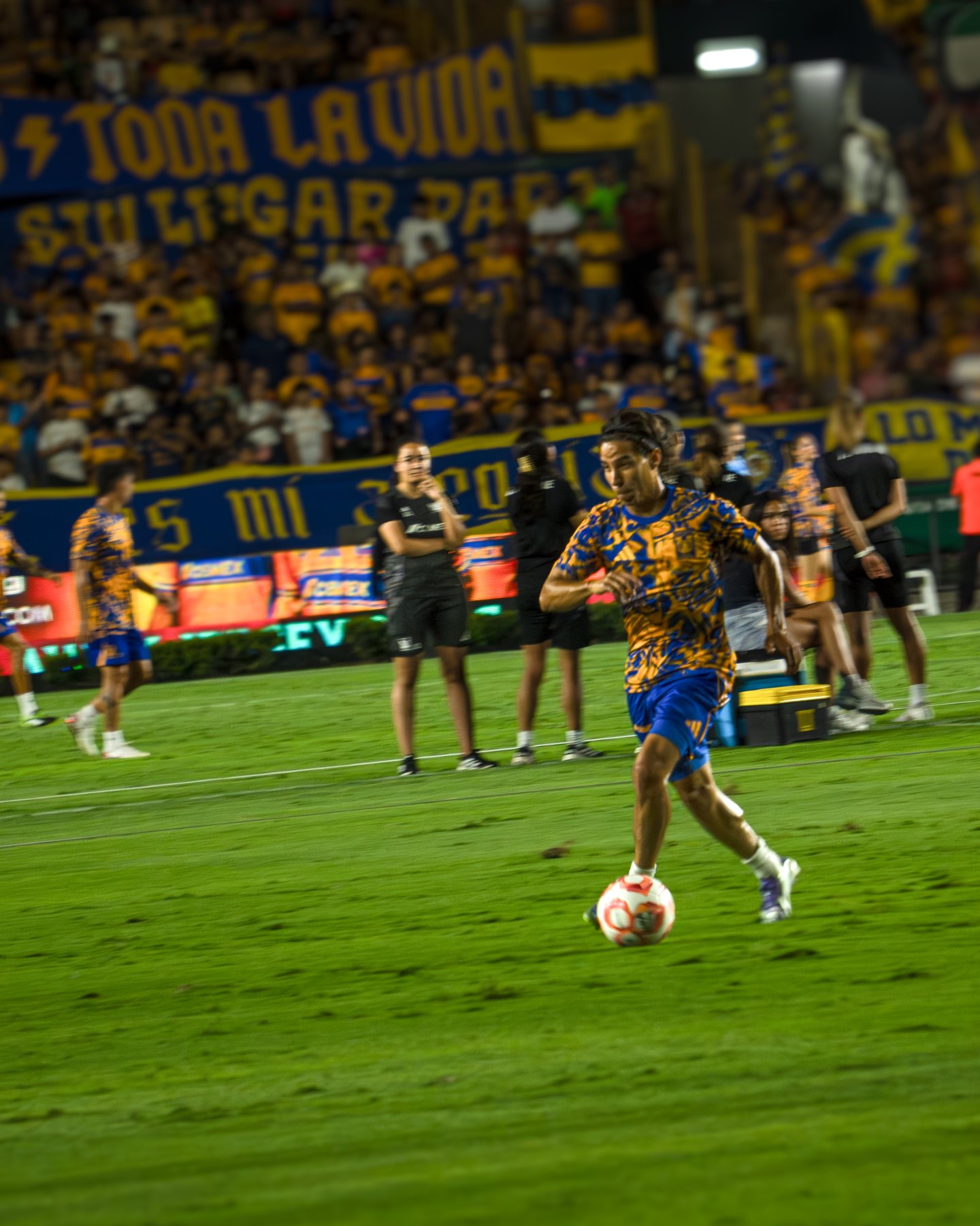 Jugadoras de Tigres corriendo tras el balón con la afición al fondo